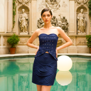 Woman in a navy corset cocktail dress with peplum waist — a classic cocktail attire look.