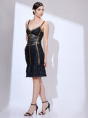 Moving left and looking back from a side angle in a bandage dress with gold trim and a tiered ruffle mermaid hem.
