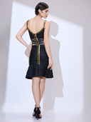 Back view of woman with one hand on waist wearing a ruffle hem dress with gold trim and sculpted bodycon fit.