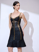 Looking right with hands on waist wearing a ruffle hem dress with gold trim and bodycon silhouette.
