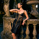 Woman wearing black bandage dress with gold trim, sweetheart neckline, midriff cut-outs and tiered ruffle mermaid hem.